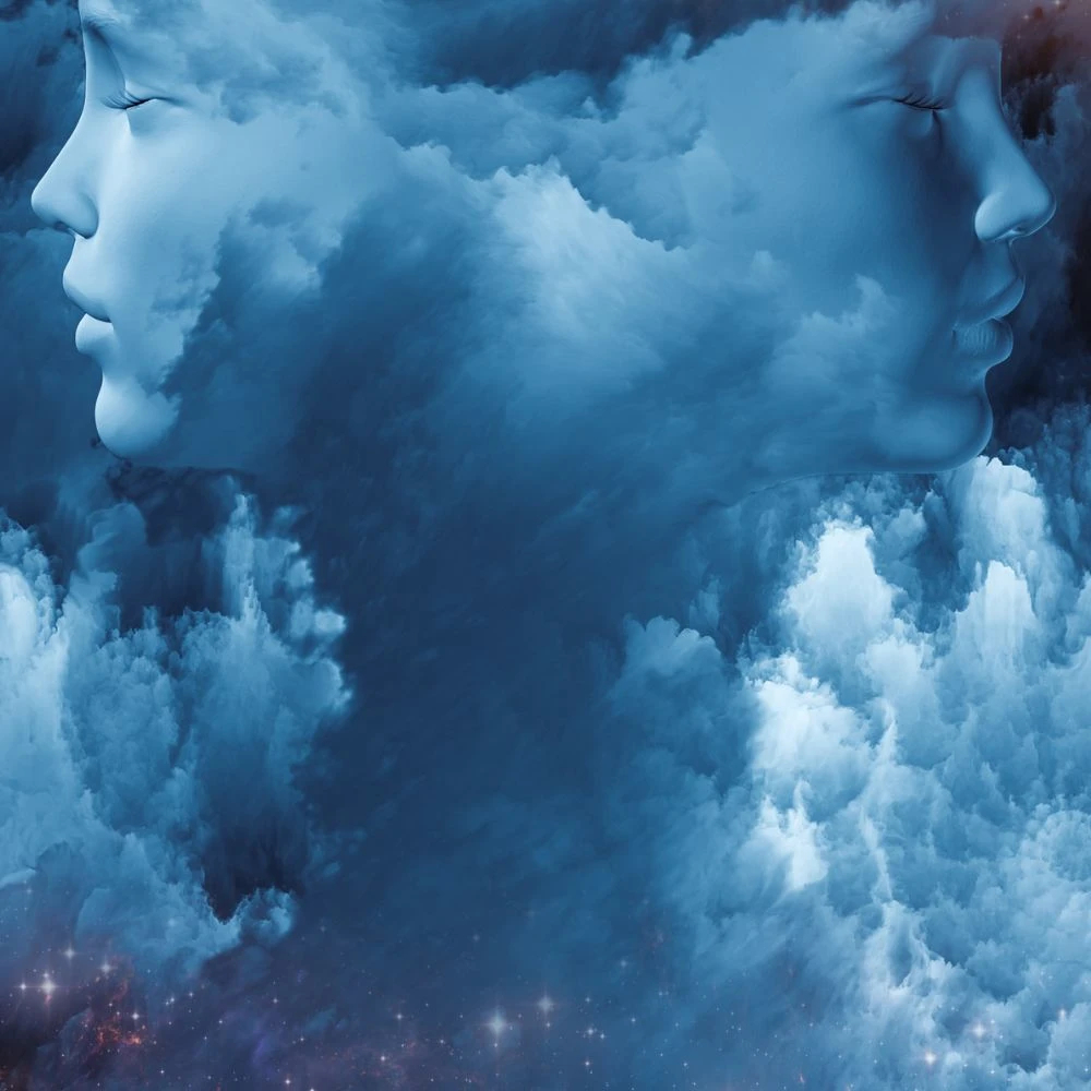 Surreal blue artwork of two serene faces formed within swirling clouds, representing dream interpretation, the subconscious, or spiritual connection.