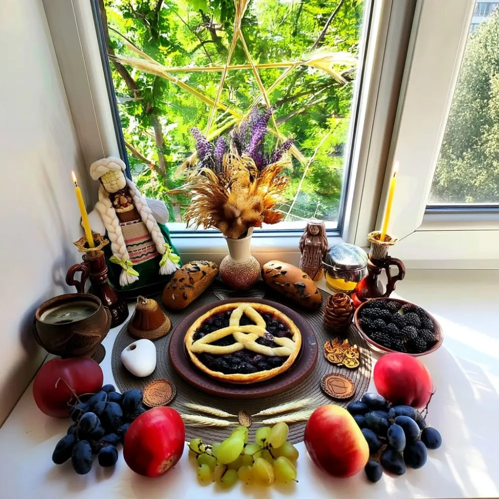 Lammas altar by a sunny window with a triple-spiral tart, apples, grapes, breads, blackberries, candles, dried herbs, and a corn dolly. A pentagram made from wheat hangs in the window, with the altar arranged in a celebration of abundance and light.