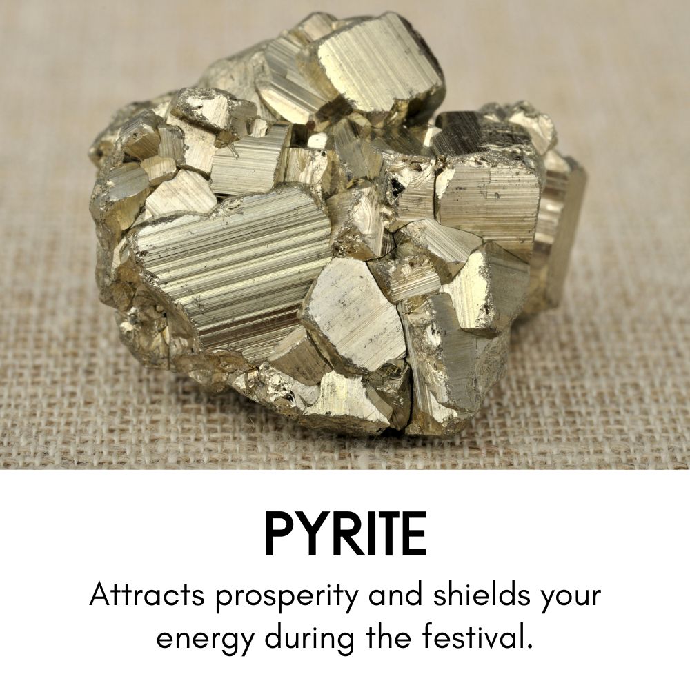Cluster of metallic gold pyrite crystals resting on a woven beige fabric. Text below reads: 'Pyrite – Attracts prosperity and shields your energy during the festival.'